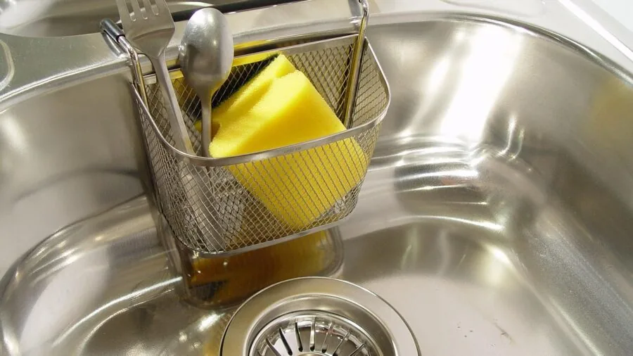 Person washing cookware in kitchen sink with soapy water, demonstrating easy cleaning and maintenance