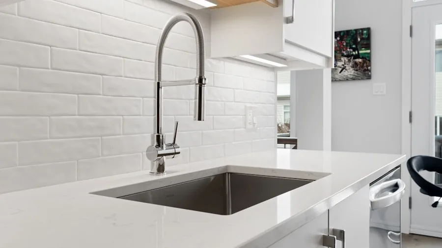 Person washing hands at a shiny stainless steel kitchen sink with water running