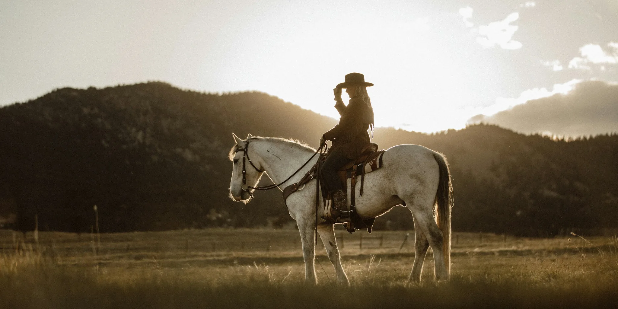 Person wearing cowboy hat outdoors in western ranch setting with natural sunlight