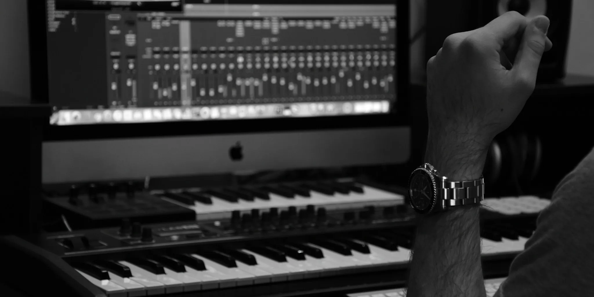 Person wearing headphones at computer desk with studio monitors for audio production work