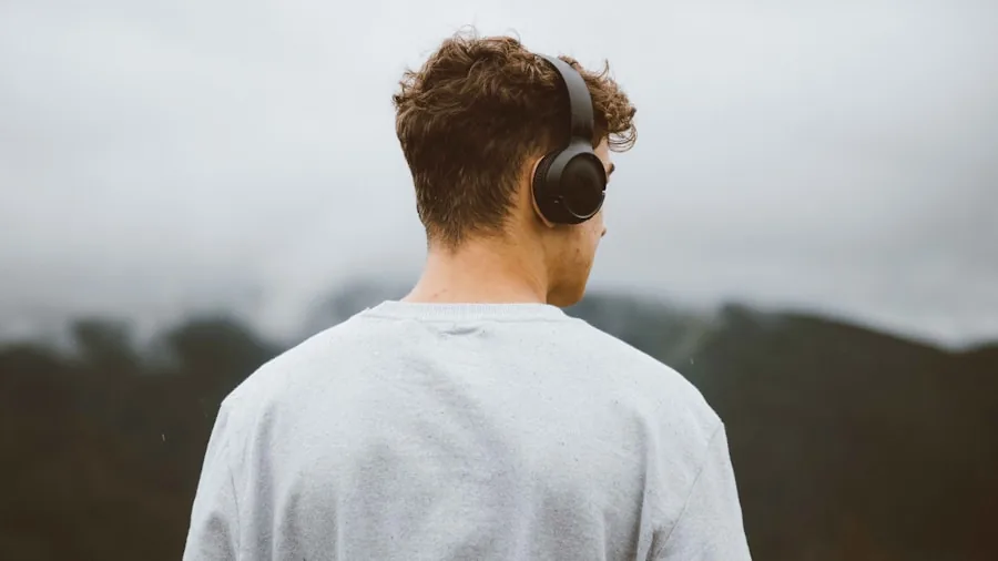 Person wearing headphones, contemplative expression while enjoying music outdoors