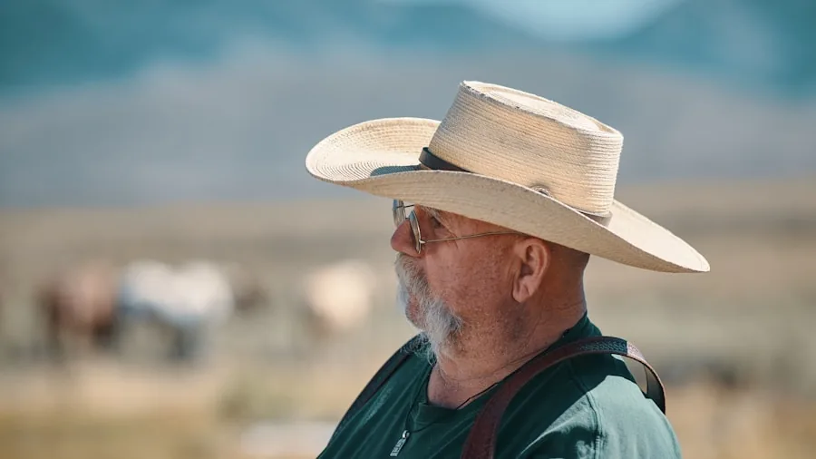 Person wearing wide-brimmed cowboy hat in outdoor ranch setting with natural sunlight