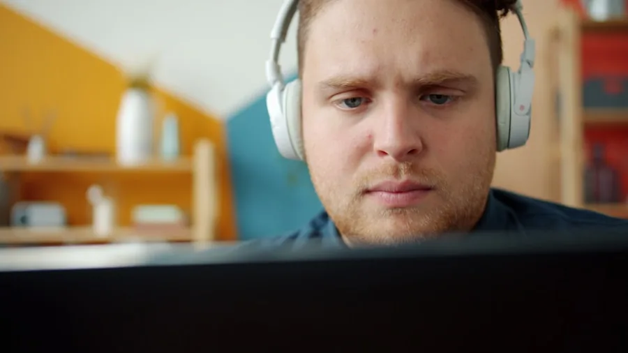Person wearing wireless headphones while working at home, demonstrating stable Bluetooth connectivity
