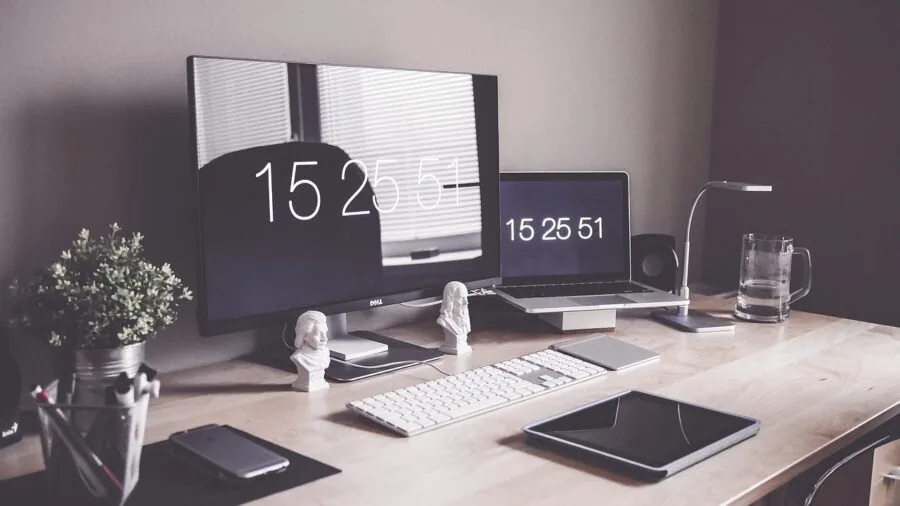 Person working at desk with wireless keyboard and laptop in modern home office environment