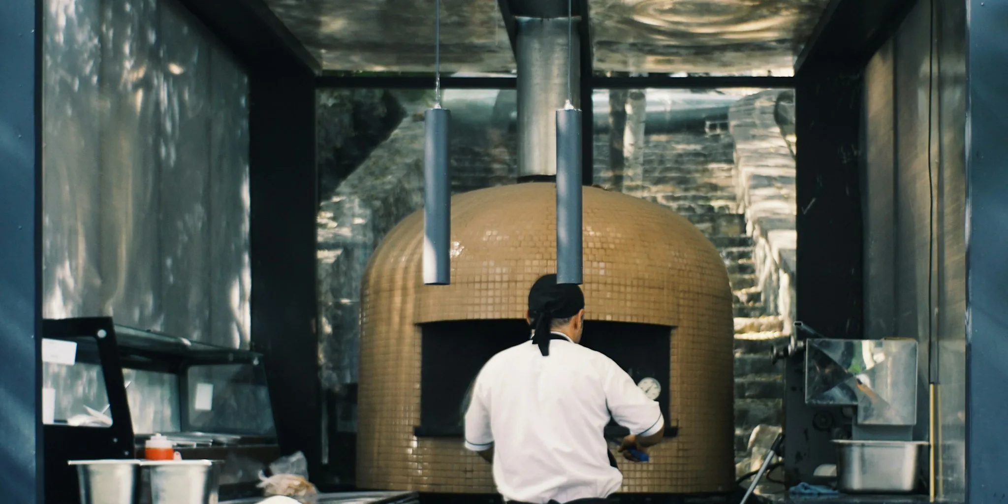 Professional baker checking freshly baked bread in modern built-in wall oven
