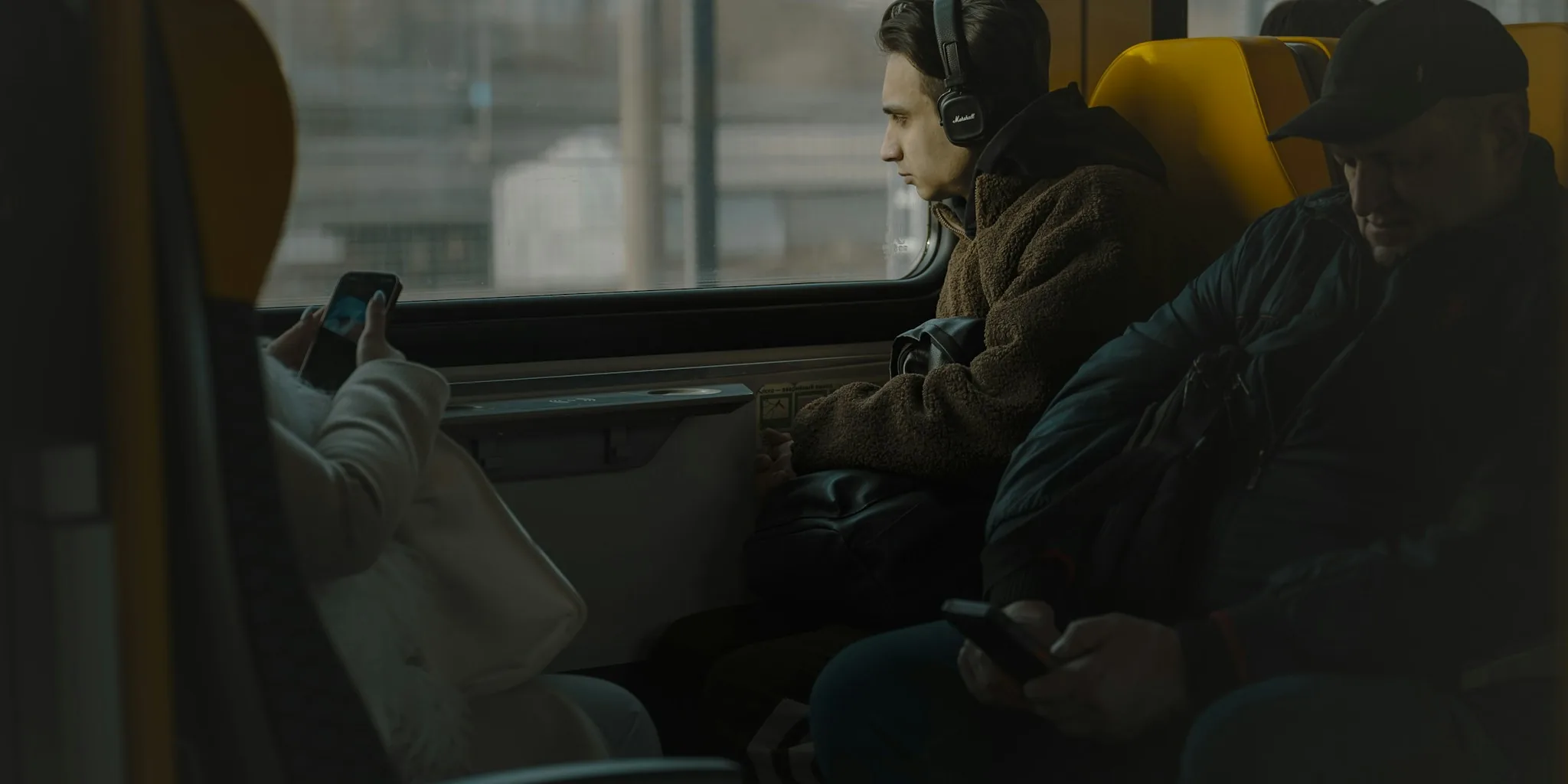 Professional commuter wearing over-ear headphones on train with natural window light
