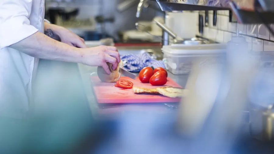 Professional cook working with quality kitchen tools while preparing fresh ingredients in a modern kitchen