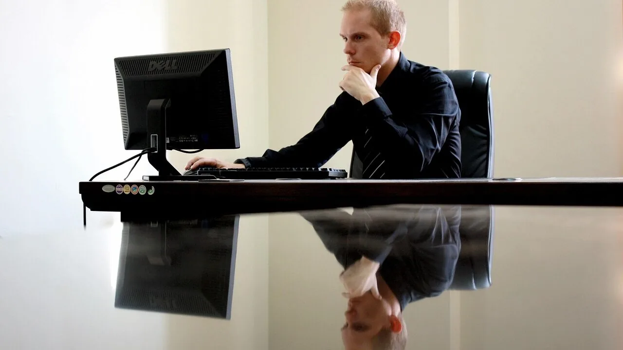 Professional sitting in ergonomic office chair at desk while working on computer