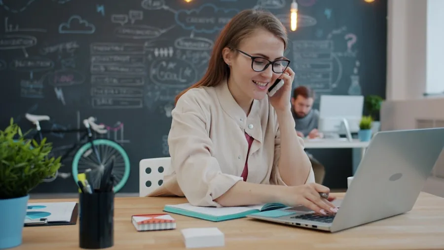 Professional woman multitasking at her desk while working on laptop and taking notes