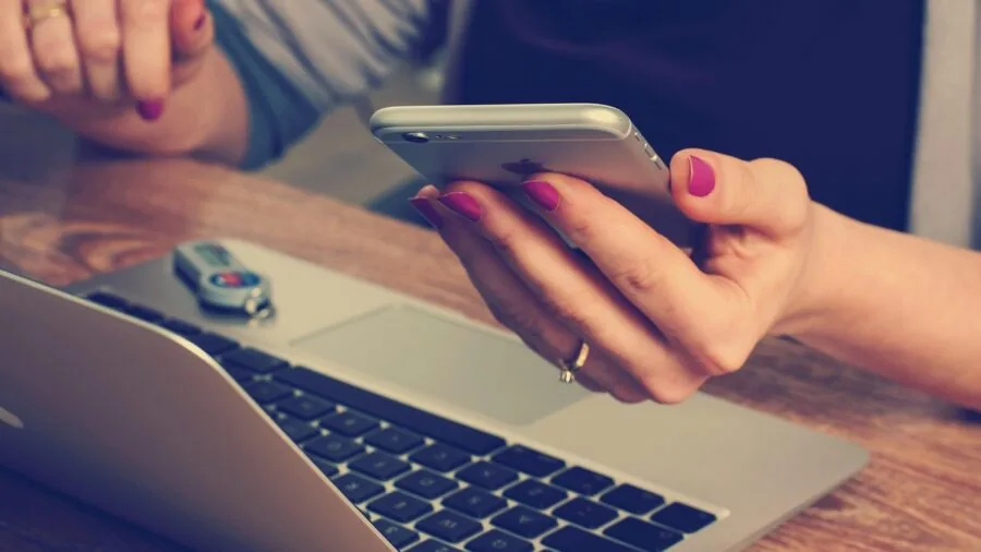 Professional working at desk with phone and laptop in modern office environment