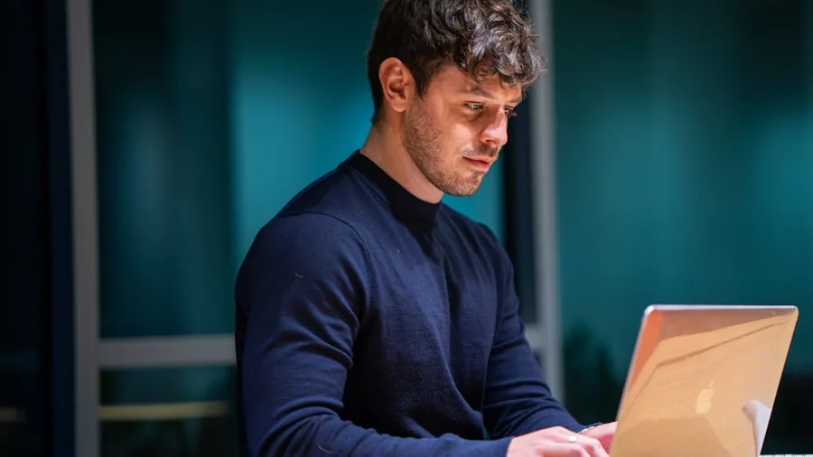 Professional working intently on laptop at desk, focused on screen with natural lighting
