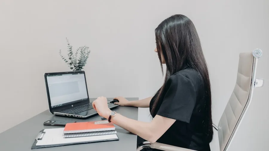 Professional working on laptop with spreadsheets and documents at desk