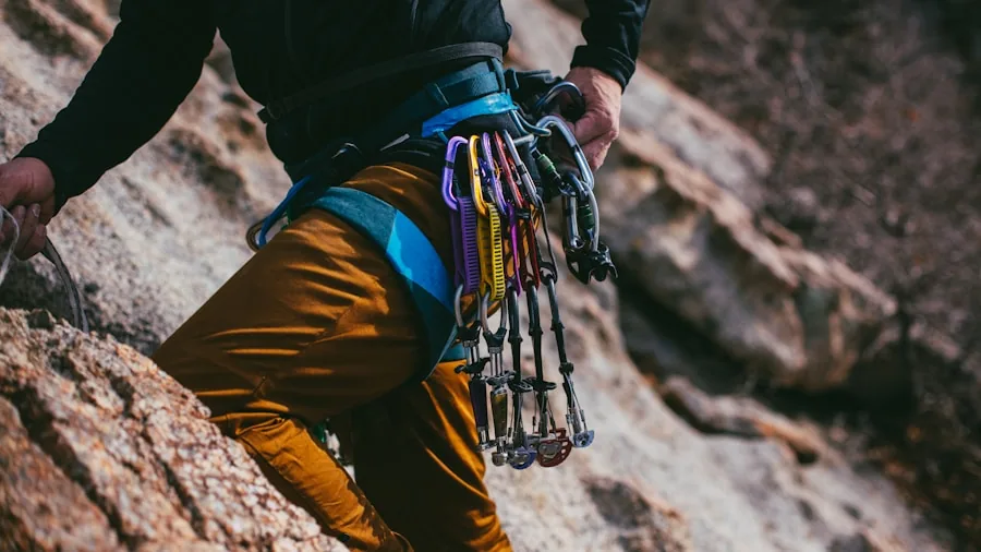 The %product_count% Best Climbing Harnesses 4 Rock climber inspecting climbing equipment and carabiners outdoors before climbing