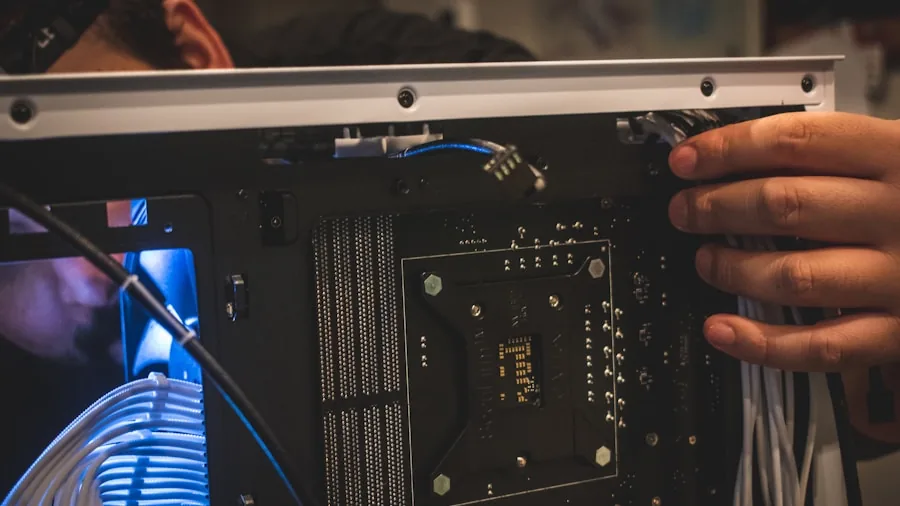 Someone installing an SSD into a desktop computer motherboard during a hardware upgrade