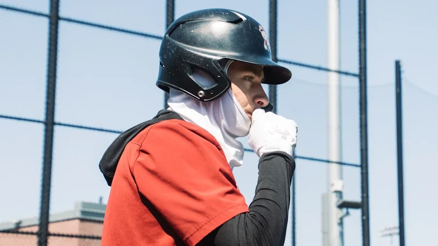 Teenage baseball player examining and comparing different gloves on field before practice