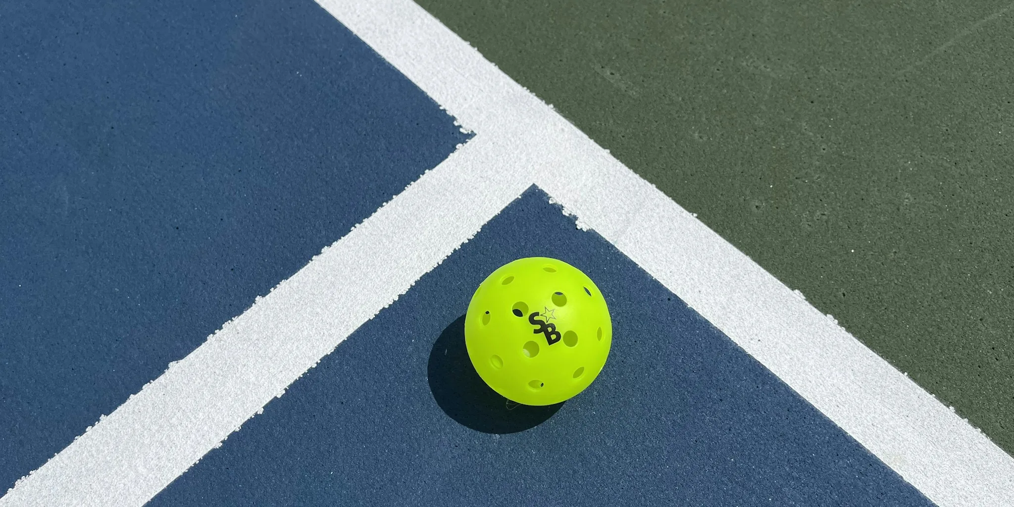 Two intermediate pickleball players actively playing on an outdoor court during daytime