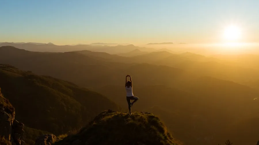 Woman doing yoga on natural mat in green garden setting during morning practice