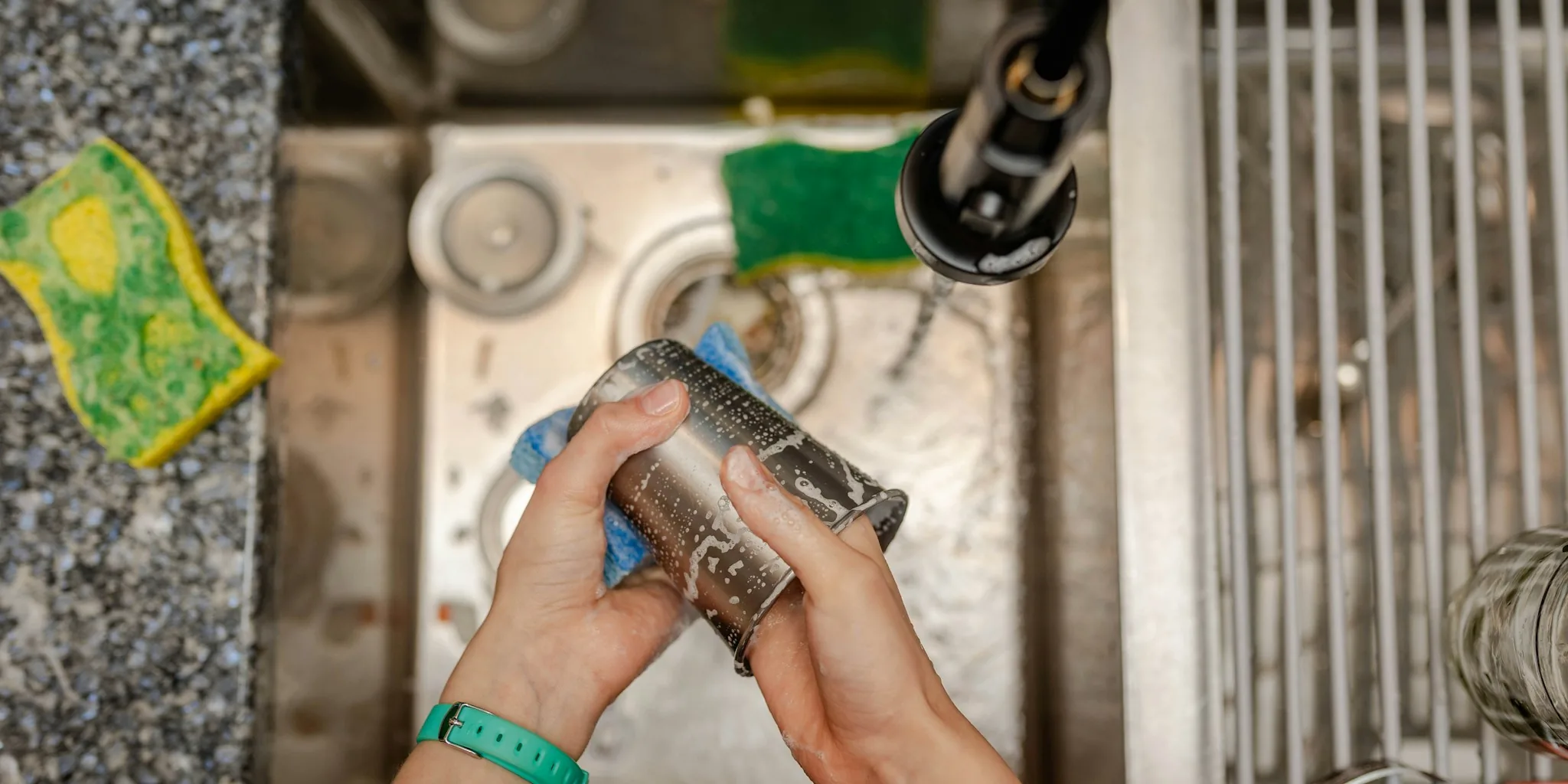 Woman washing dishes at kitchen sink with natural light streaming through window