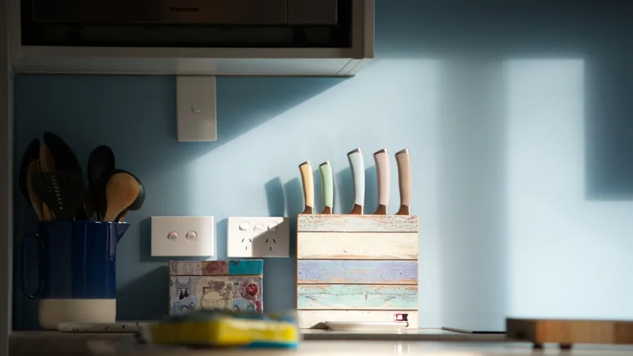 Wooden knife storage block on kitchen counter with natural lighting and cooking ingredients nearby