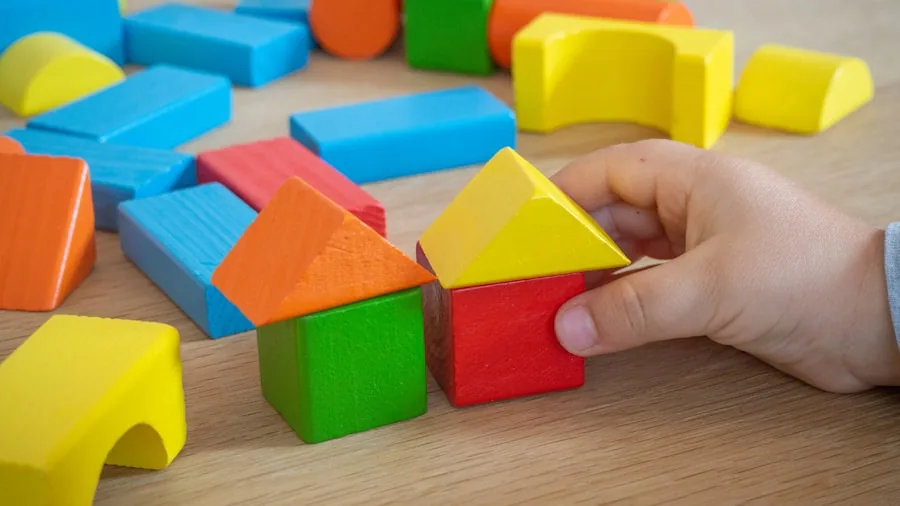 Young child focused on building with colorful blocks at a table indoors